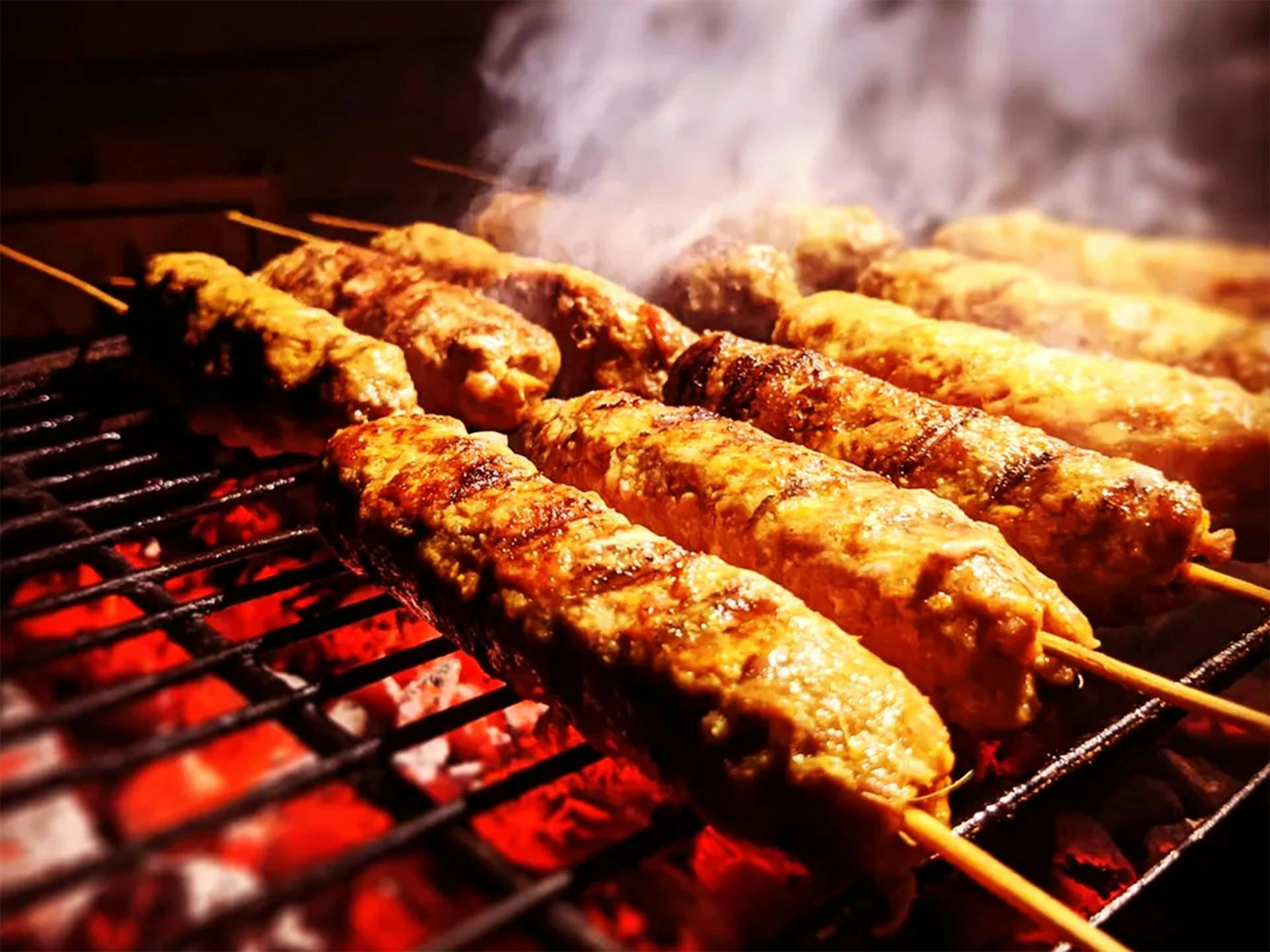 Meat skewers on a grill with red hot coals and smoke