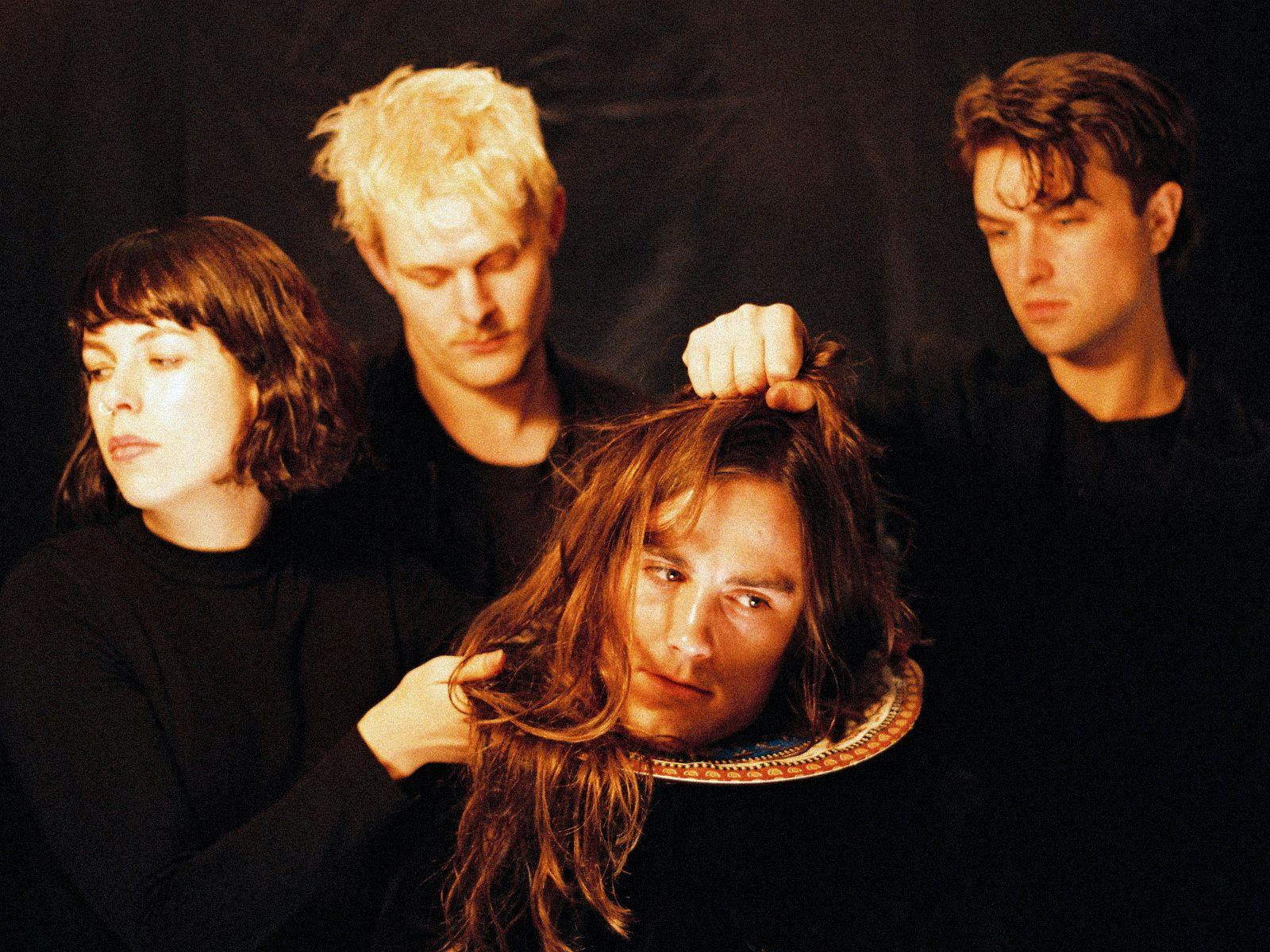 Members of bitumen pose, a member at the front pretends their head is on a plate.