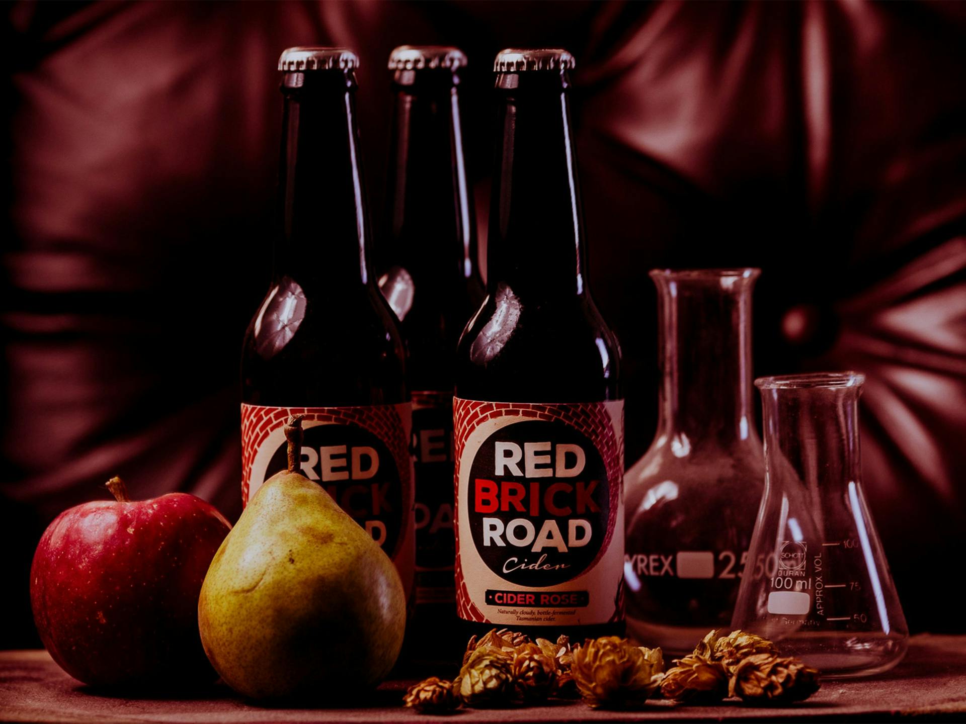 Bottles of cider sit next to fruit 