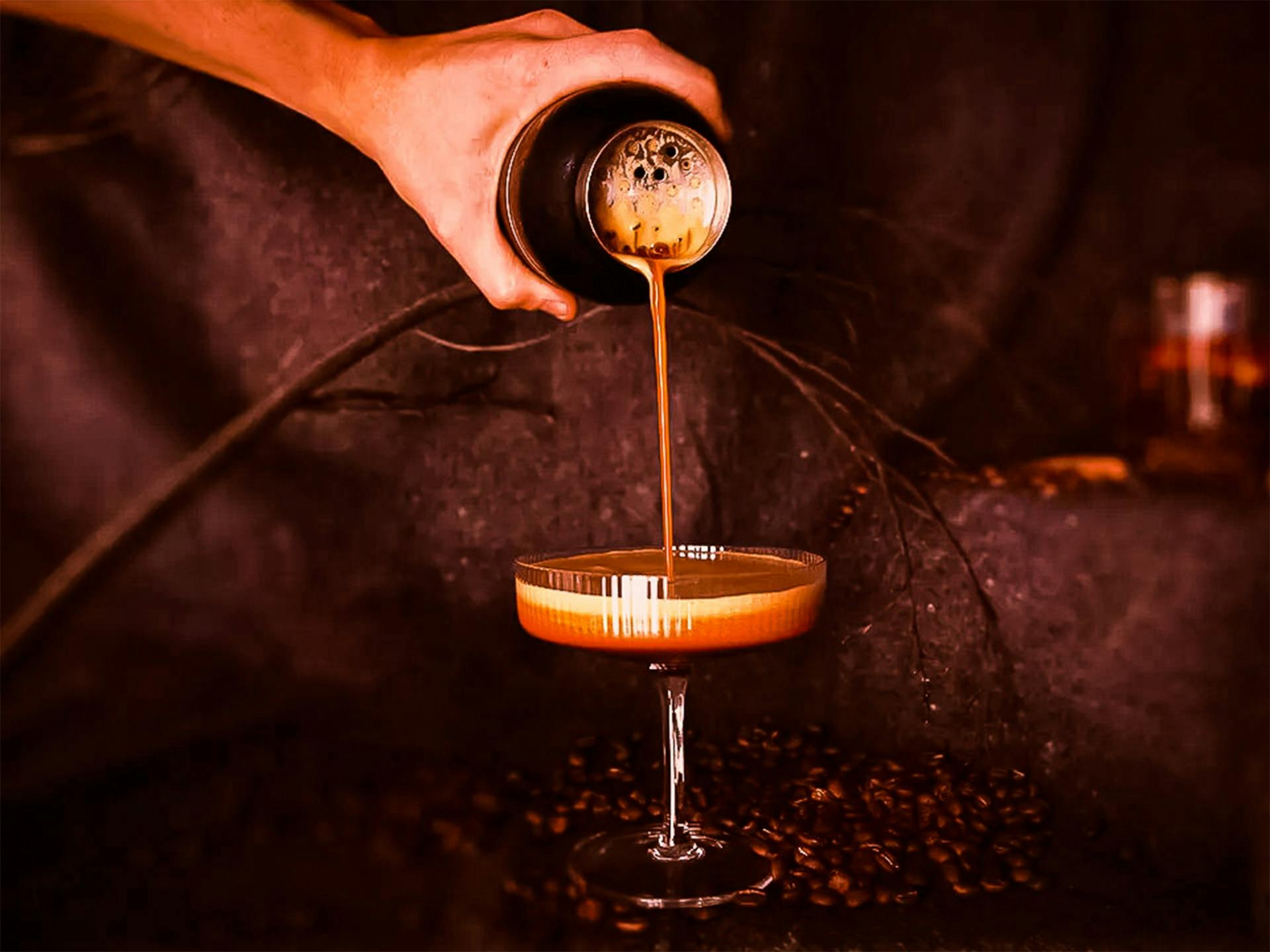 An espresso martini being poured into a coupe glass