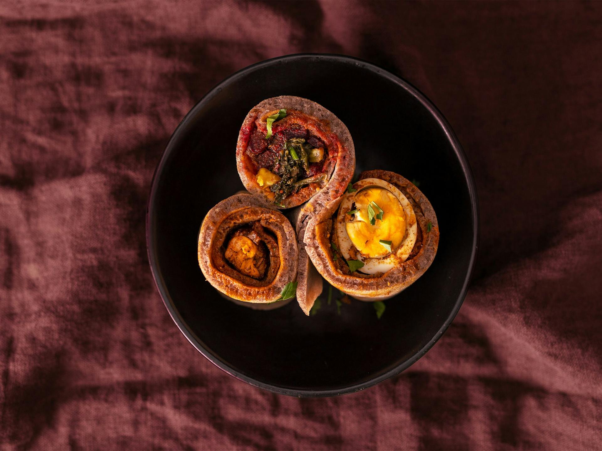 Three injera in a bowl, atop a linen tablecloth