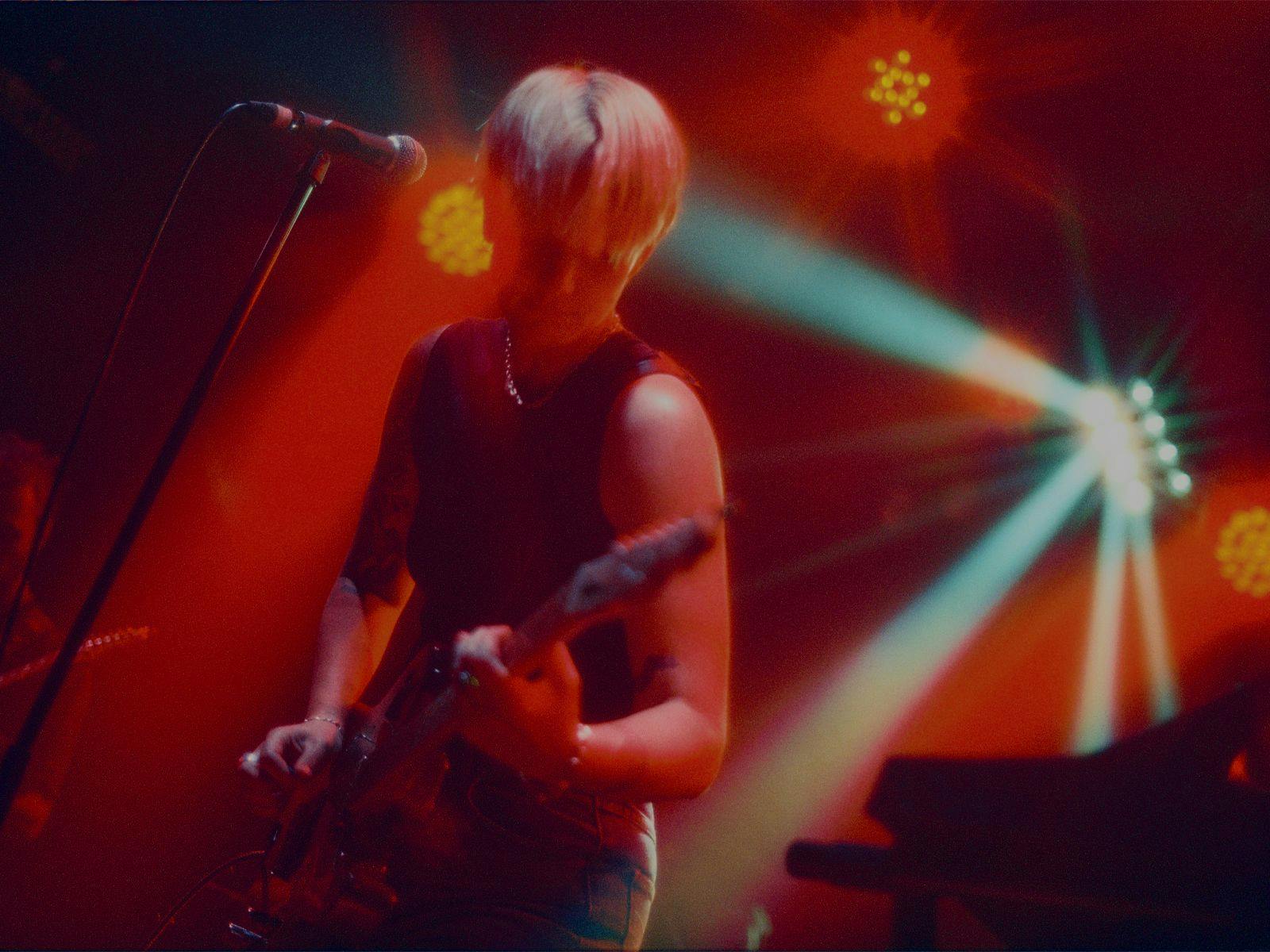 Enola performing on stage, guitar in-hand.