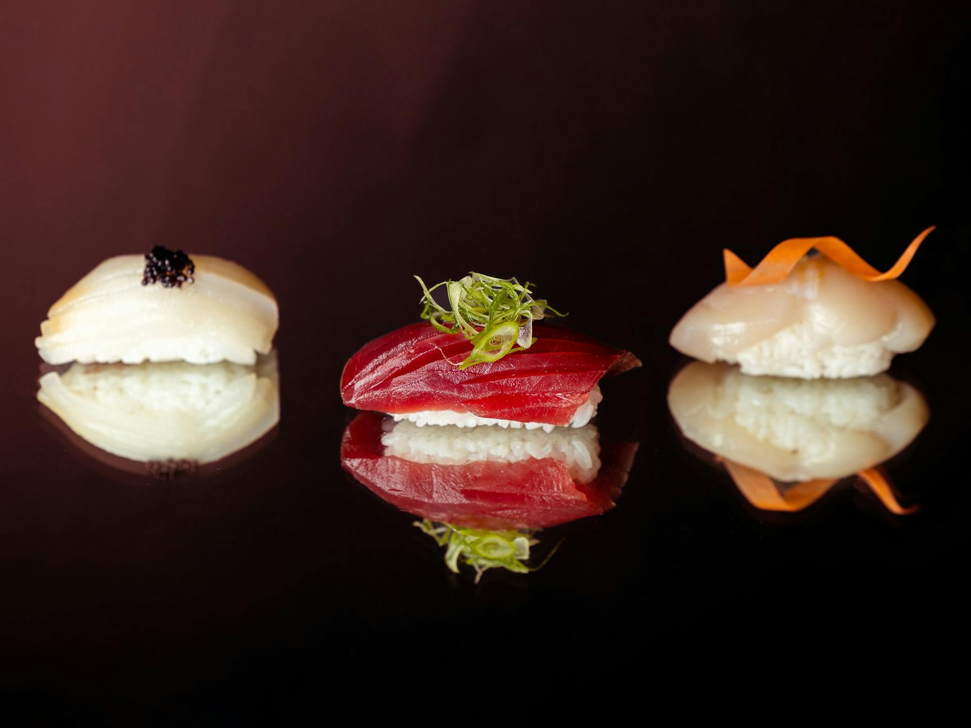 Three nigiri sushi sit on a mirror