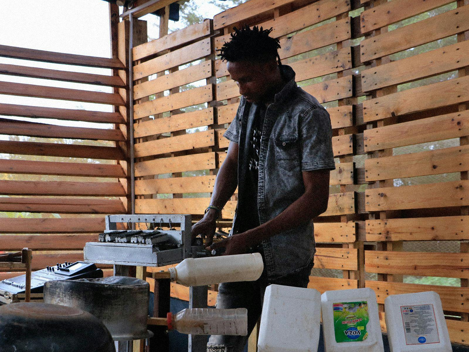 A man tinkers with a homemade instrument, made from garbage.