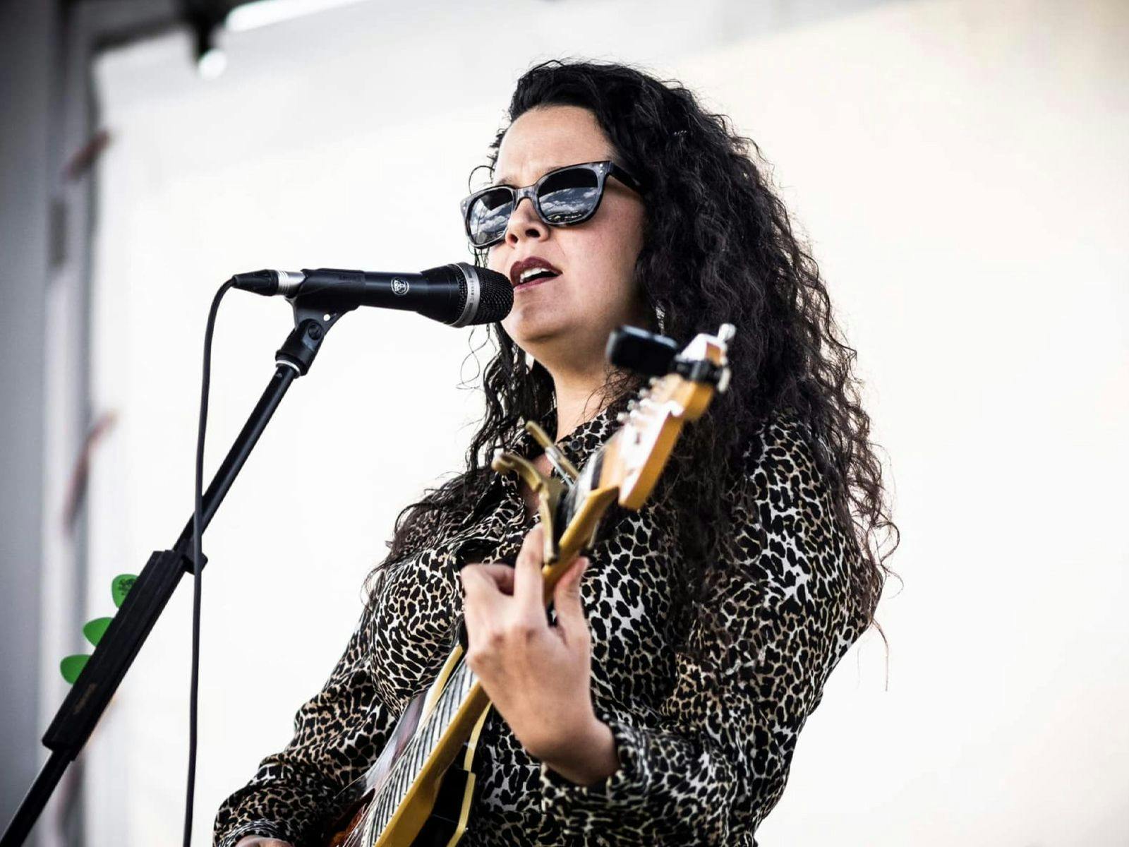 MADELENA performing on-stage, playing the guitar.