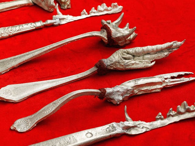 Several strange metal eating utensils, with animal features in place of blades or prongs.