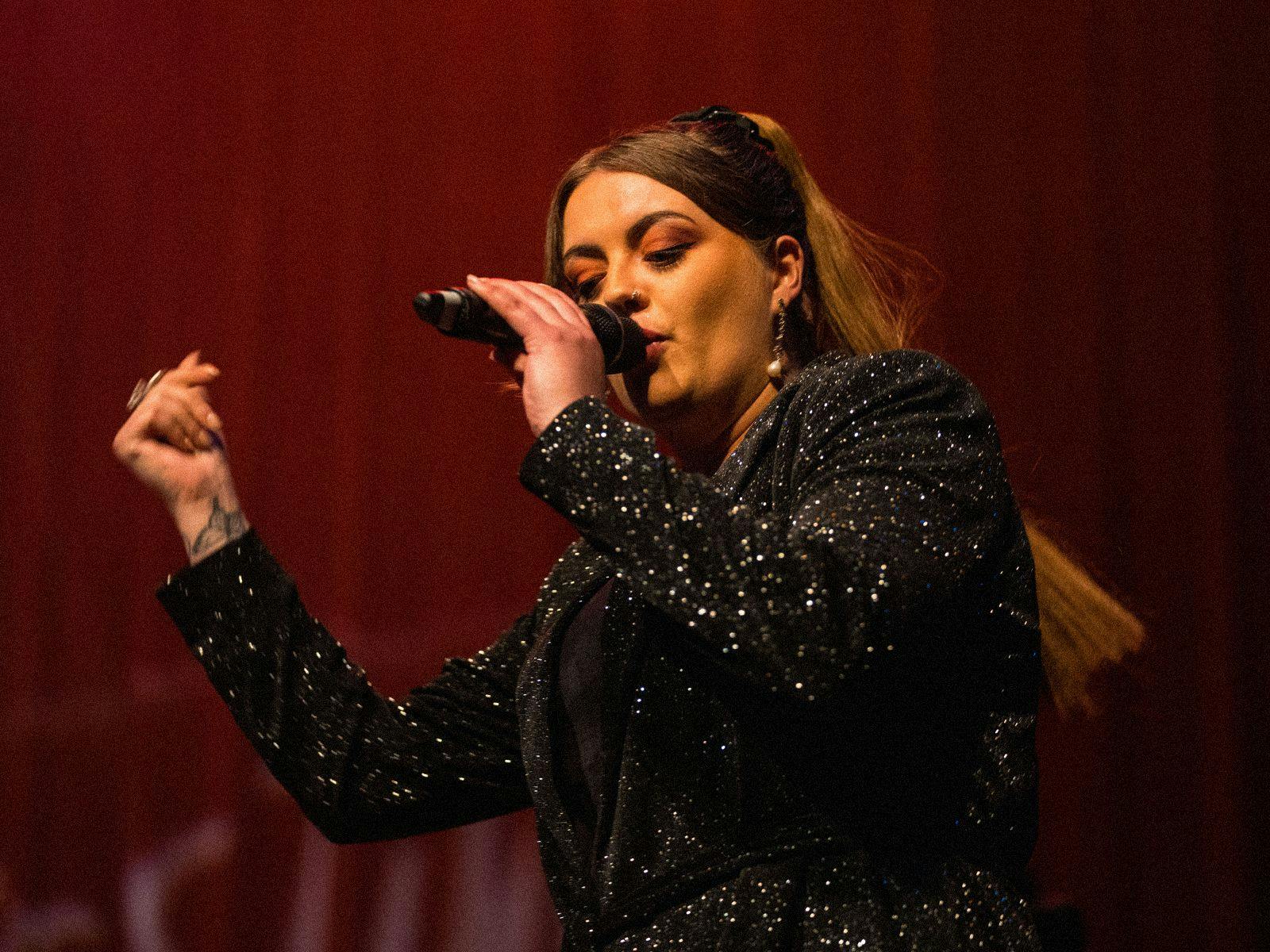 DENNI performing with a microphone in hand.