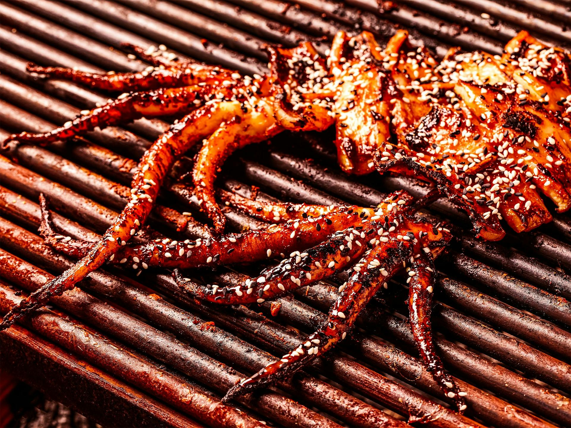 Whole squids on a grill, sprinkled with sesame seeds