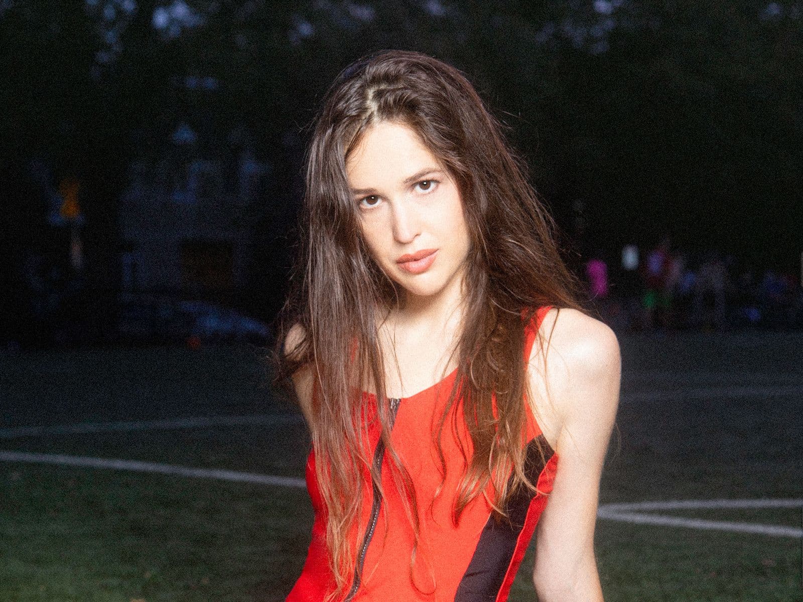 Marie Davidson sits on an outdoor sports field.