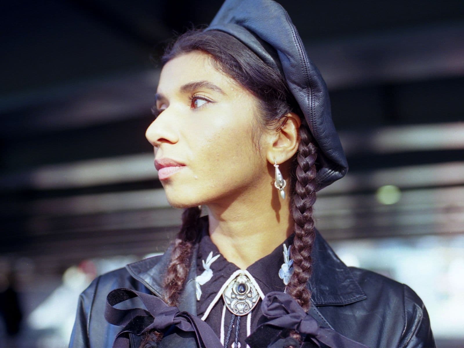 Nabihah Iqbal looks to their side, wearing a leather jacket and cap.