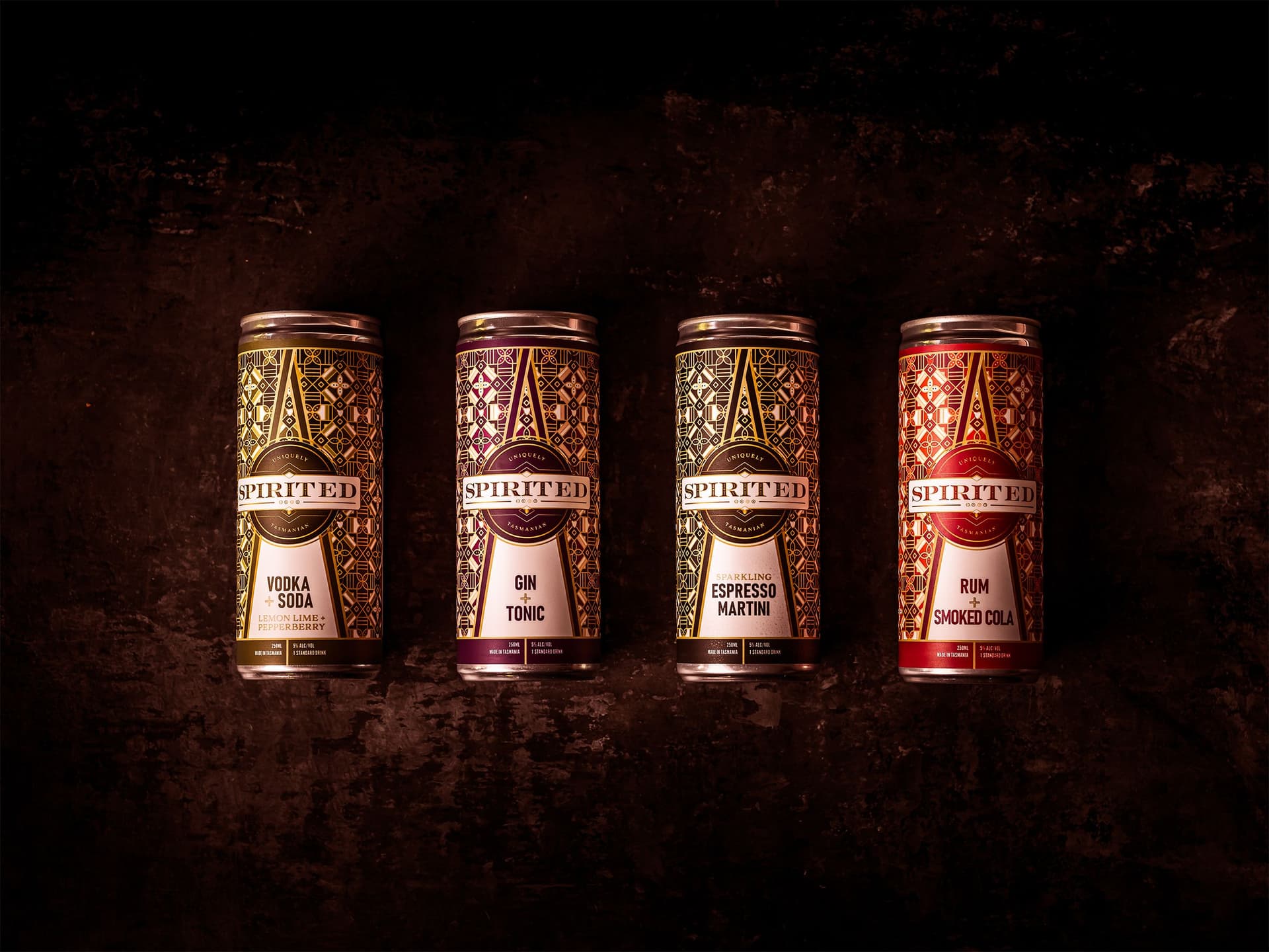 Four cans of pre-made cocktails lie on a black background